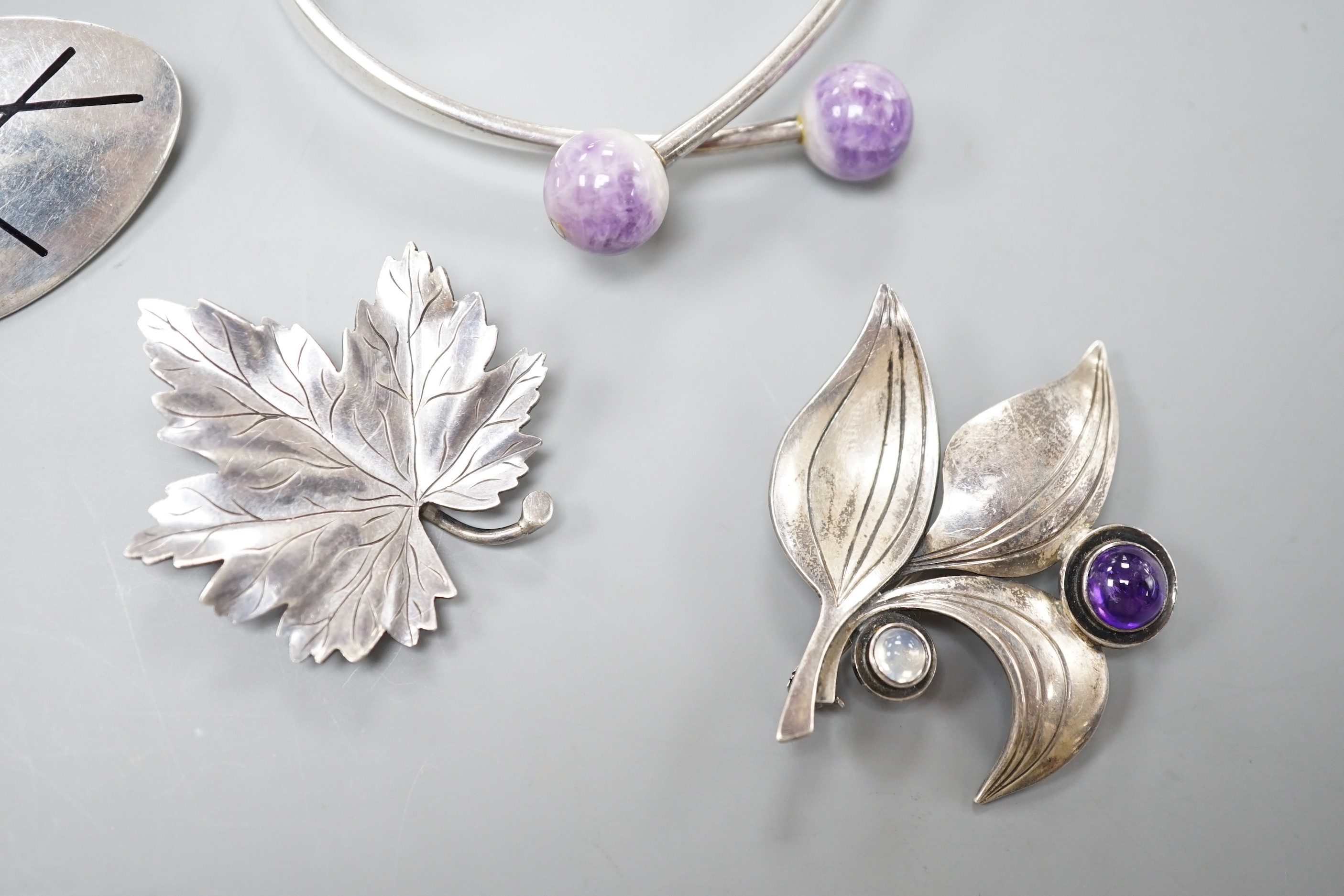 Four items of 20th century Scandinavian white metal jewellery, including a brooch and amethyst quartz set bangle by Hans Hansen and two Swedish white metal leaf brooches, bangle interior diameter 62mm.